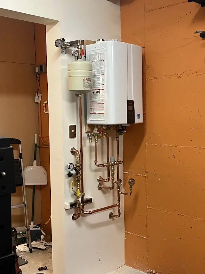 Plumbing technician inspecting water heater connections in Rockingham